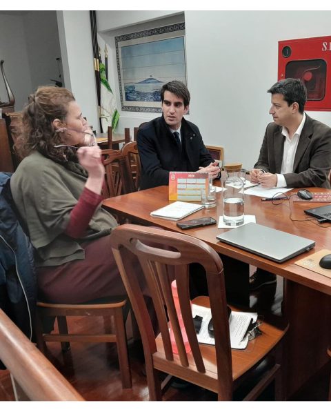 Reunião institucional entre representantes da Junta de Freguesia do Bonfim e da Casa dos Açores do Norte, sentados à mesa em conversa de trabalho.