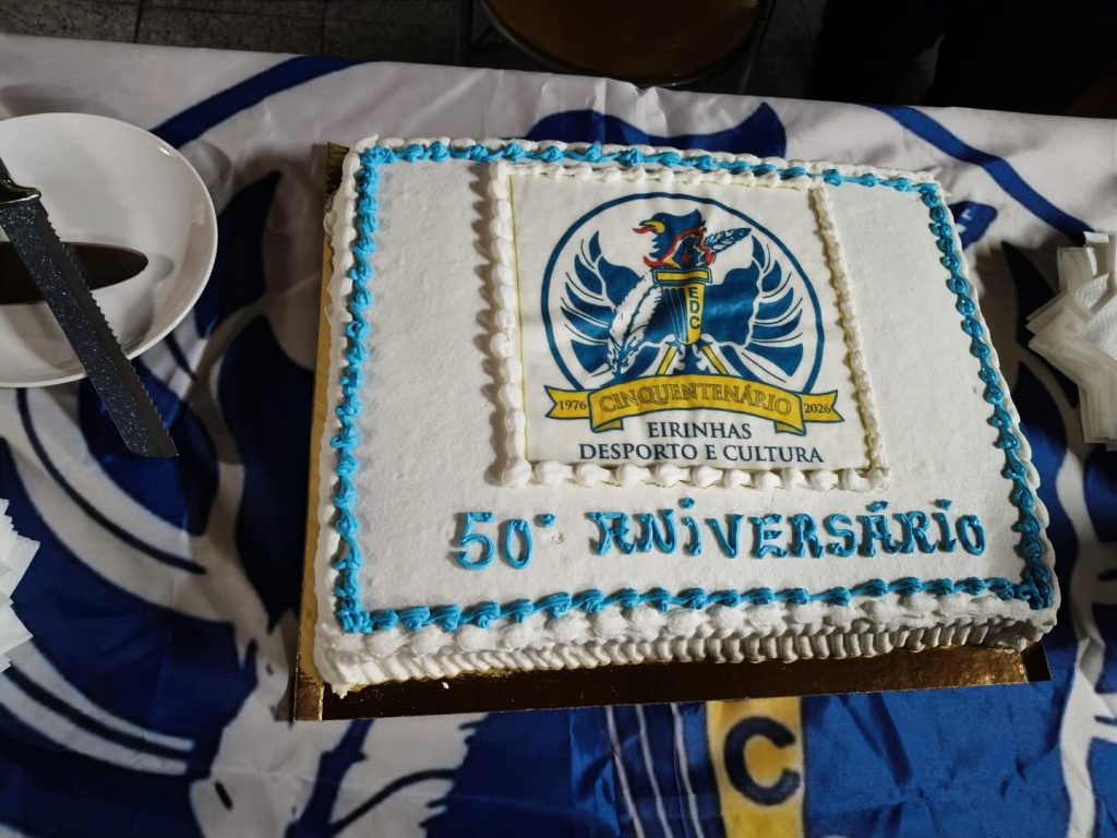 Celebração dos 50 anos do Eirinhas Desporto e Cultura com bolo e momento simbólico, com presença de representantes da Junta de Freguesia do Bonfim.